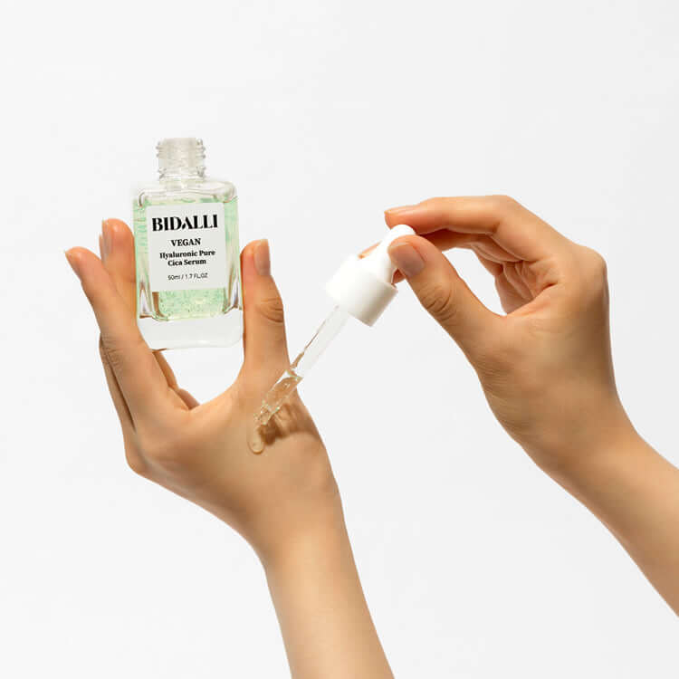 Hands applying Bidalli Vegan Hyaluronic Pure Cica Serum with dropper on the back of hand