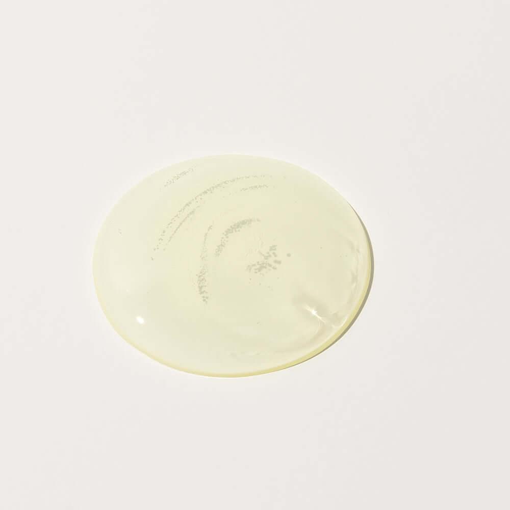 Close-up of transparent yellow serum texture from Bidalli Vegan Tone-Up Pure Vita Serum on white background