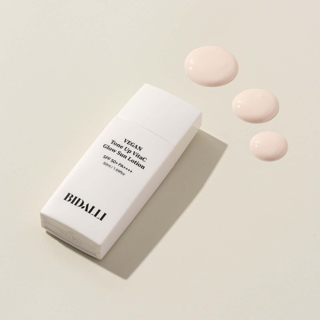 Bidalli Vegan Tone Up VitaC Glow Sun Lotion with SPF 50+ PA++++, shown with soft pink cream texture swatches, brightening vegan sunscreen for radiant and protected skin