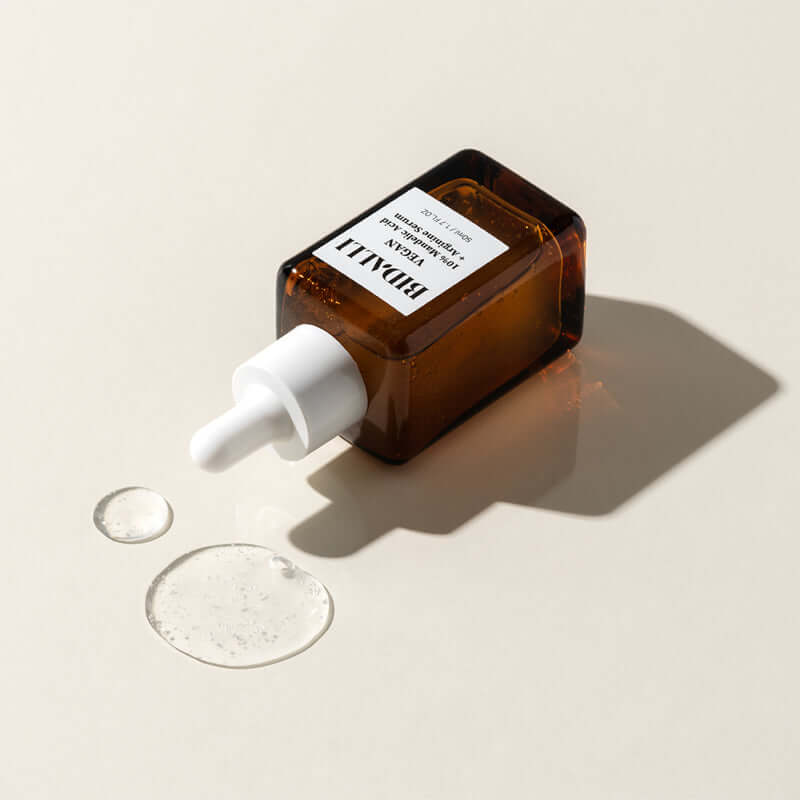 Bidalli Vegan 10% Mandelic Acid + Arginine Serum with visible clear gel texture drops on surface, vegan exfoliating serum in amber dropper bottle for glowing and smooth skin