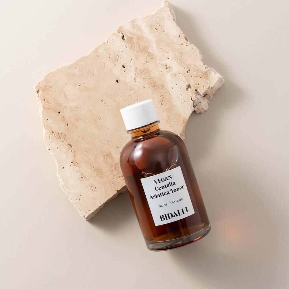 Bidalli Vegan Centella Asiatica Toner in amber glass bottle, placed on natural stone slab, soothing vegan toner for calming sensitive and irritated skin, 160ml