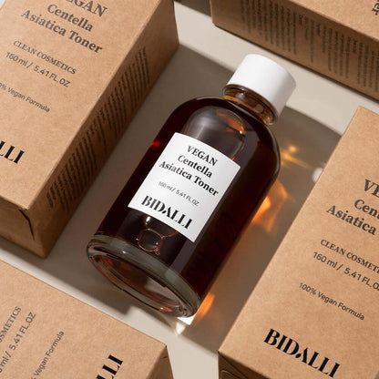 Bidalli Vegan Centella Asiatica Toner bottle surrounded by kraft packaging boxes, calming vegan toner for sensitive skin with eco-friendly branding, 160ml