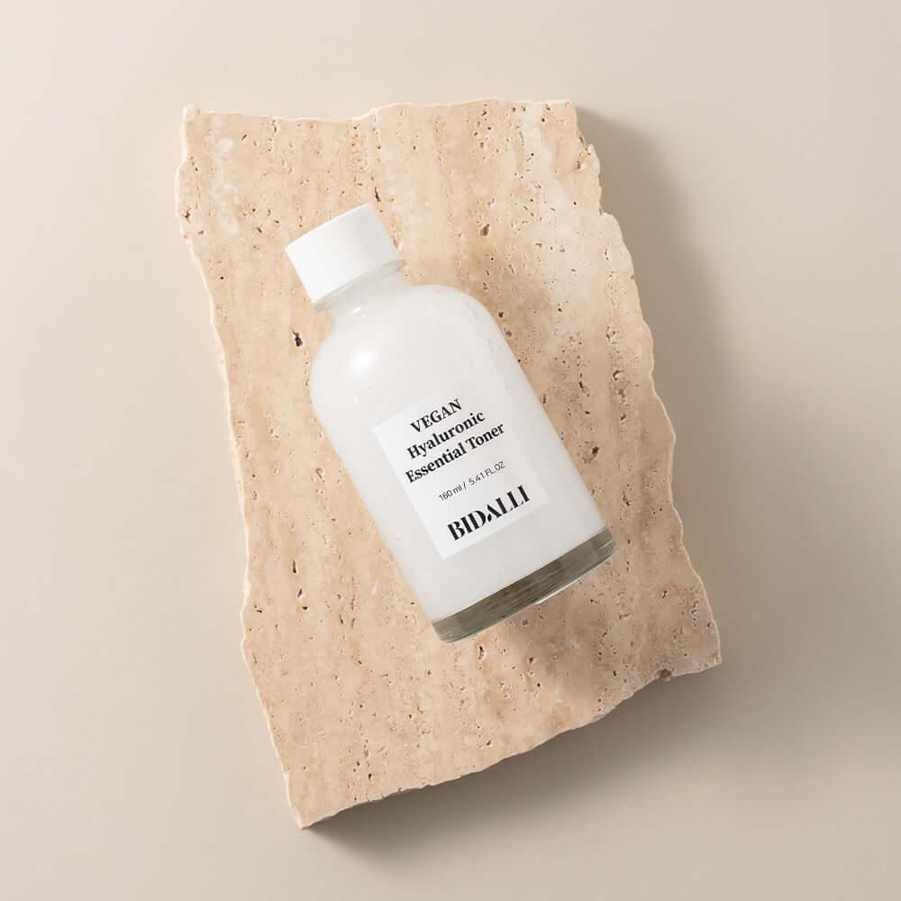 Bidalli Vegan Hyaluronic Essential Toner in clear glass bottle, placed on natural stone slab, deeply hydrating vegan toner for soft and moisturized skin, 160ml