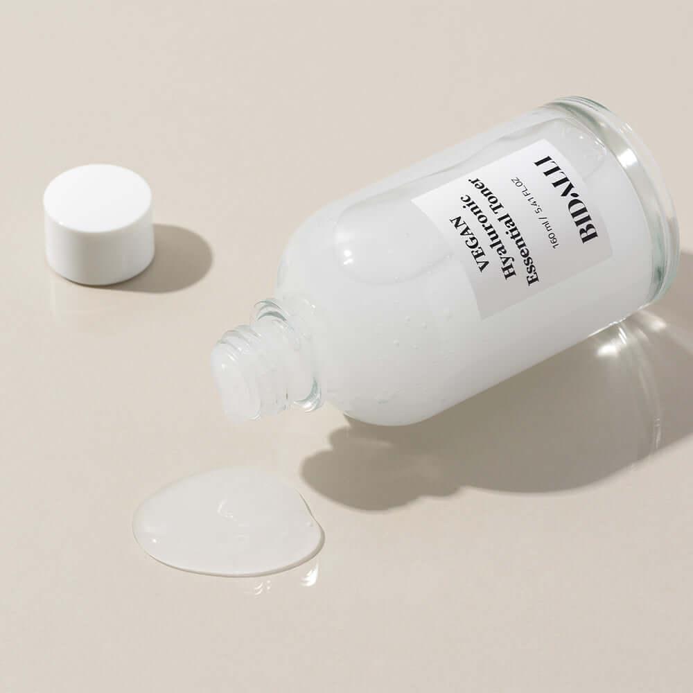 Bidalli Vegan Hyaluronic Essential Toner bottle tipped over with visible liquid texture spilled on surface, lightweight hydrating vegan toner for dewy and moisturized skin